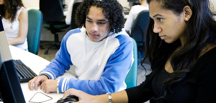Two youth work at a computer completing their individualized mentoring plans.