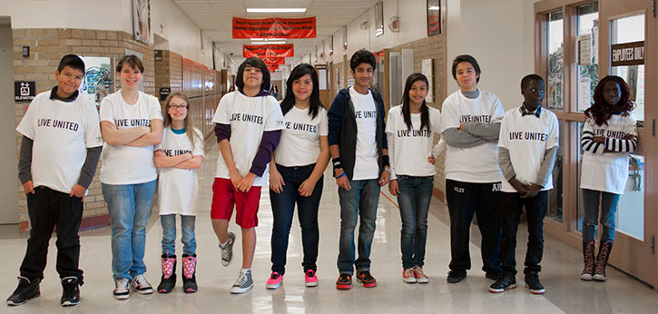 A group of middles school students wearing United Way "Live United" t-shirts stand in their school hallway.