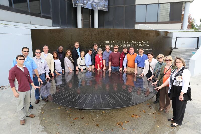 Group standing around commemorative fountain. 