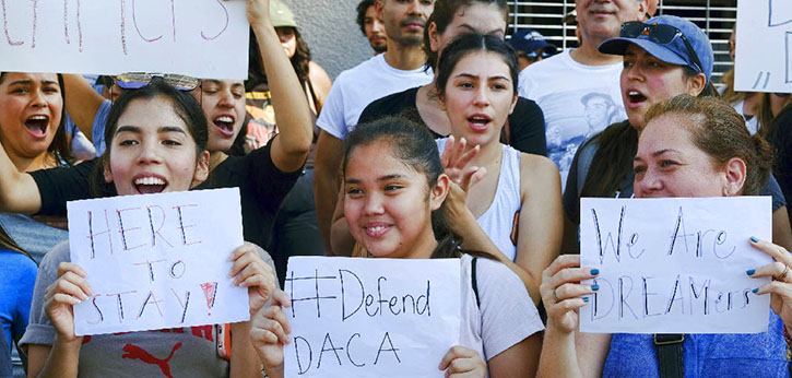 A group of Dreamers at a rally to preserve the Deferred Action for Childhood Arrivals program hold up #DefendDACA signs.
