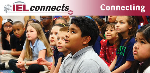 @IELconnects - Connecting: A group of students sit together in their community school.