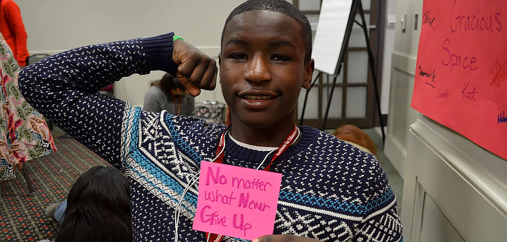 Boy with his arms up and a post-it that states Never give up